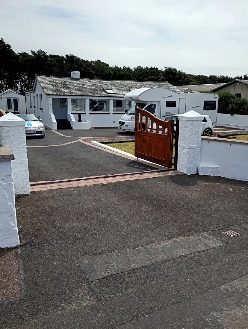 Wide view of a white painted bungalow and matching white boundary pillars