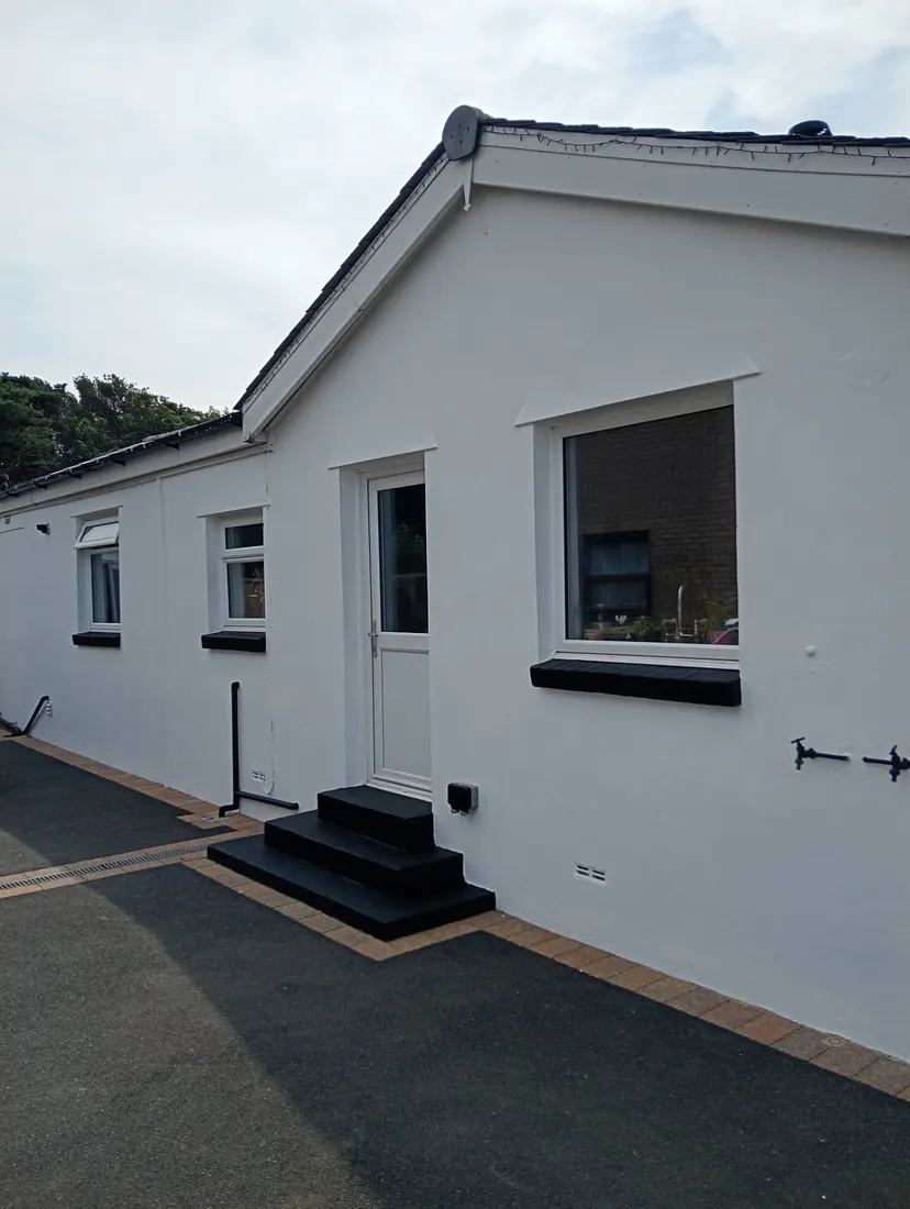 Side elevation of a bungalow with bright white painted walls and dark trim